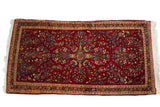 Dark red mid-century Persian Sarouk rug, vibrant gem-tone floral motifs, plush pile.
