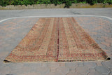 Traditional antique Persian Kerman rug folded lengthwise, showing thin profile and floral pattern.