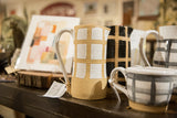 Handmade ceramic gridded white and beige pitcher with speckled texture.