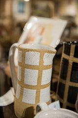Handmade white and beige ceramic pitcher, highlighting the speckled gridded texture.