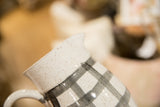 Hand-painted black gingham pattern on a speckled ceramic pitcher.