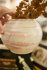 Handmade ivory and blush ceramic vase held in hand, showing its size and finish.