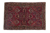 Antique German Sarouk rug with dense floral sprays in cherry red, navy blue, and gold tones.