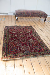 Angled view of an antique Sarouk rug's dense floral pattern on a cherry red ground.