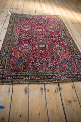 Angled perspective of an antique Sarouk rug, showing the dense floral sprays on a cherry red field.