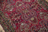 Hand-knotted texture of dense floral sprays on the cherry red field of an antique Sarouk rug.