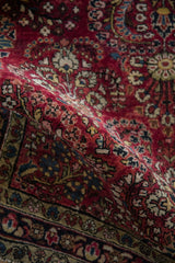 Close-up of the cherry red pile and dense floral sprays on a folded antique Persian Sarouk rug.