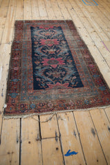 Tattered side of the antique Hamadan rug, with raspberry red border and navy blue floral field.