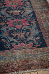 Antique Hamadan rug close-up: navy field, raspberry floral, reciprocating sickle leaves, and wear.