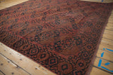 Antique Ersari rug corner showcasing sharp serrated floral border and dusty raspberry gul medallion.