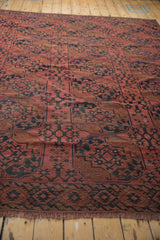 Antique Ersari rug close-up: serrated border, dusty red, navy gul medallions, and even wear.