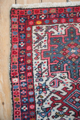Corner of a vintage Karaja rug with red floral border, dark selvage, and ivory fringe.