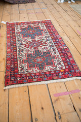 Angled view of a vintage Persian Karaja rug's triple medallion and colorful geometric field.