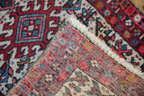 The hand-knotted back and colorful geometric wool pile of a vintage Karaja rug.