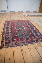 Hand-knotted Karaja rug section with cherry red field and geometric navy blue border.