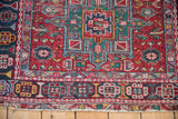 Cherry red field and navy border of a vintage Karaja rug with geometric blossoms.