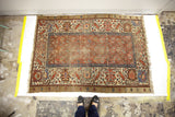 Worn red central field of an antique Persian Bakshaish rug with camel border and fringe.