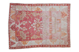 Vintage distressed Oushak rug with central palmette, floral vines, heavy abrash in raspberry, orange, ivory.