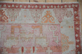 Distressed Oushak rug corner with pale raspberry red geometric border and even wear to knot heads.