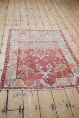 Distressed Oushak corner shows soft raspberry, pink, and beige floral motifs with abrash.