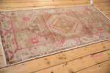 Distressed Oushak rug corner with hot pink floral details, copper, and worn ivory pile.