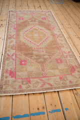 Distressed vintage Oushak rug runner showing worn foundation and hot pink floral corner details.