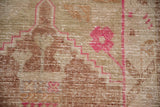Distressed Oushak rug: hot pink geometric lines on worn olive and copper foundation.