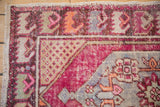Vintage Oushak rug corner detail, fuchsia, beige, tangerine spandrel with faded pile.