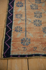Distressed vintage Oushak rug's tangerine abrashed field, navy floral motifs, fuchsia zig-zag border.