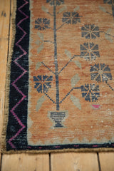 Distressed Oushak rug close-up: navy zig-zag border, geometric florals on tangerine field.