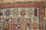 Distressed Oushak rug detail showing textured pile, rust-orange starbursts, blue elements, and natural fringe.