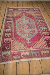 Distressed Oushak rug corner detail with seed spandrels and floral border in magenta, blue.