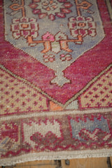 Close-up of vintage distressed Oushak rug showing magenta, pale blue patterns and even wear.