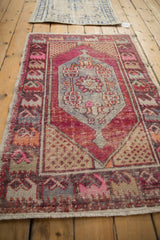Distressed Oushak rug corner: beige seed spandrel with magenta and pink blossom border.