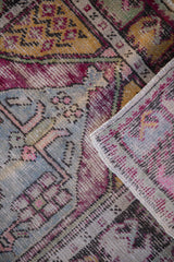 Textural distressed pile of a vintage Oushak rug, showing exposed knot heads and side selvage.