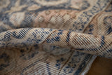 Distressed, low-pile texture of a hand-knotted Turkish rug with visible knot heads.