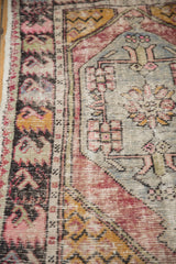 Distressed Oushak rug showing worn pile, original selvage, and geometric saffron border.