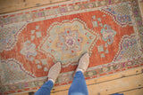 A top-down view showing the scale of a distressed Oushak runner with a rust, blue, and seafoam medallion.