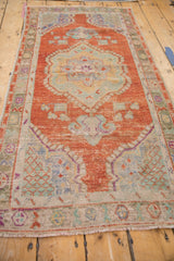 Angled view of a distressed Oushak runner, showcasing its rust medallion and faded blue details.