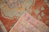 Flipped corner of a distressed Oushak rug showing the hand-knotted back and low pile.