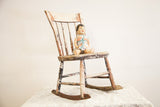 Antique primitive children's rocking chair, circa 1800s, with chippy white, dark green, and red paint and aged wood.