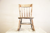Antique children's rocking chair back view with chippy white, green, and red paint.