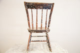 Primitive children's chair back with chippy white, dark green, red paint, and a visible seat crack.