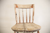 Antique children's rocking chair back and seat, displaying chipped white, green, red paint and a rustic crack.