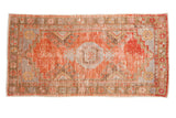 Vintage distressed Oushak runner featuring a faded rust medallion and blue, brown geometric motifs, 2'7