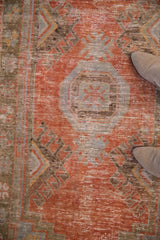 Distressed vintage Oushak rug detail: worn rust-red pile, faded blue, and brown traditional motifs.