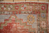Distressed Oushak runner detail with rust stepped pattern, pale blue field, saffron pinwheel flower, showing wear.