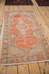 Distressed texture of vintage Oushak runner, highlighting rust and pale blue floral border.