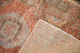 Distressed Oushak rug's folded corner, showing worn rust and blue pile with visible foundation.