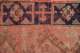 Distressed vintage Oushak rug's navy Lotto border meets worn tomato red pile.